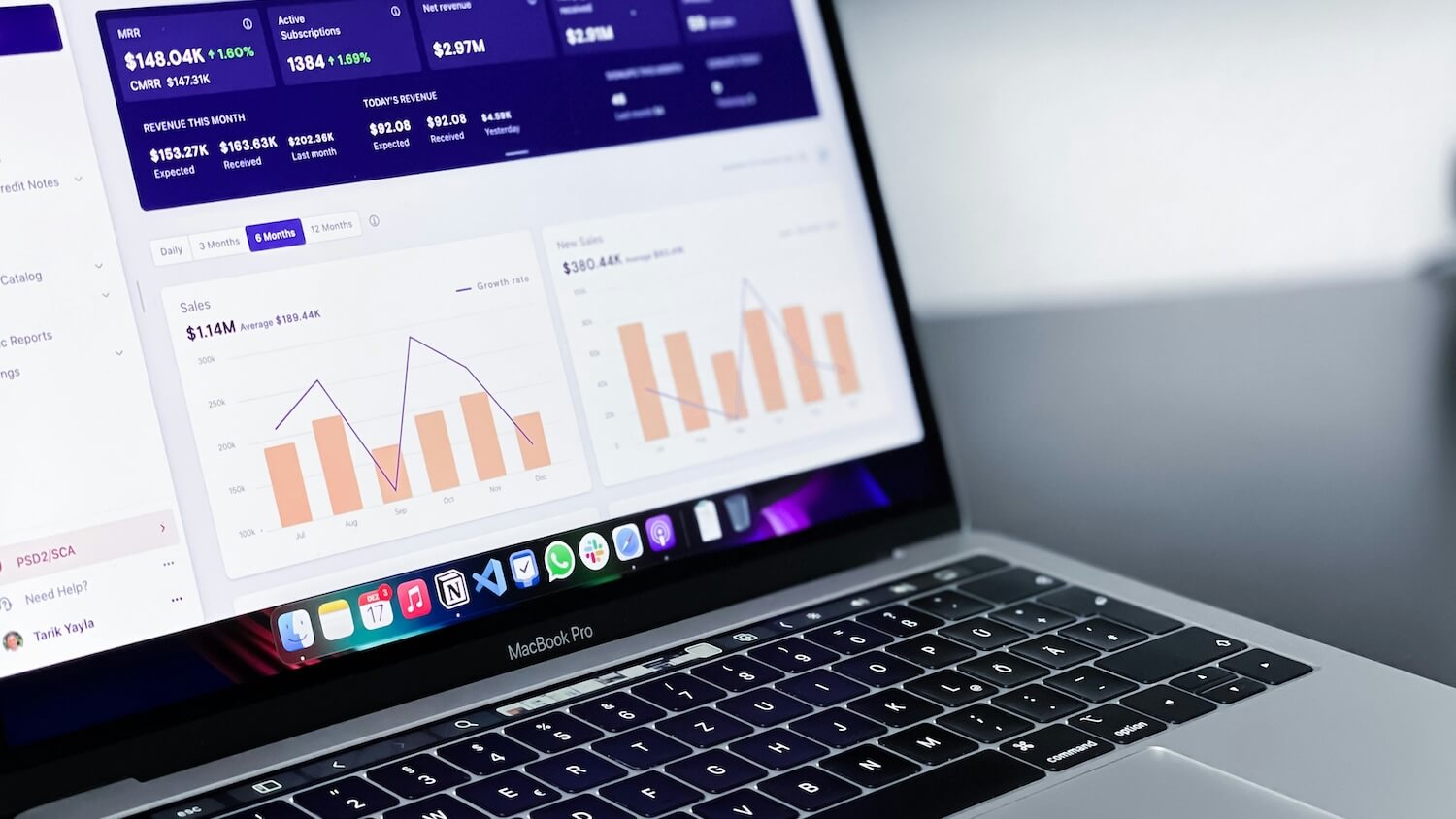 MacBook Pro displaying a SaaS subscription analytics dashboard with MRR, revenue charts, and active subscription metrics.